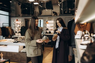 Naklejka premium Women choosing sneakers in modern boutique fashion store