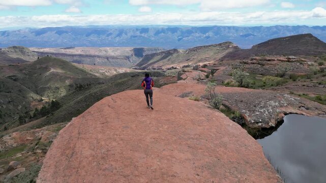 Flyover: Woman walks to sandstone escarpment viewpoint in Bolivia