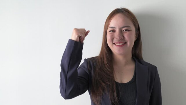 Portrait of a young Asian businesswoman against white background celebrating with arms raised up
