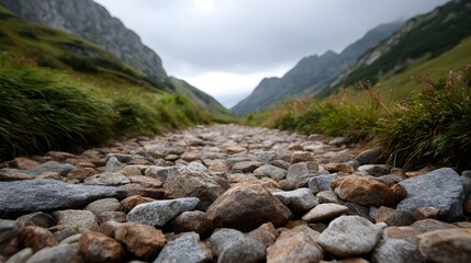 Fototapeta premium A low angle view of a rocky mountain path winding through a dramatic valley under a cloudy sky