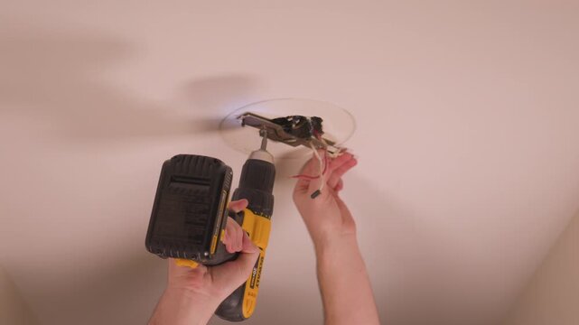 Removing the mounting bracket from the ceiling box in close up.