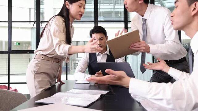 Stressful leader watches frustrated colleagues having a heated argument over documents, pointing fingers and escalating tension while discussing unsatisfactory work at unsatisfactory work performance