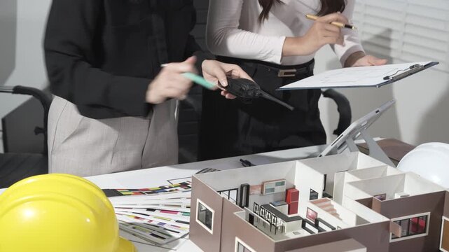 Architects reviewing building model and plans in design meeting