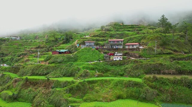 Wide push out aerial of the asphalt highway and tiered rice terraces disappearing into the thick, rolling clouds of Buguias, Benguet, Philippines.
