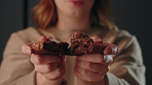 Slow motion of hands breaking chocolate cookie with gooey melted center