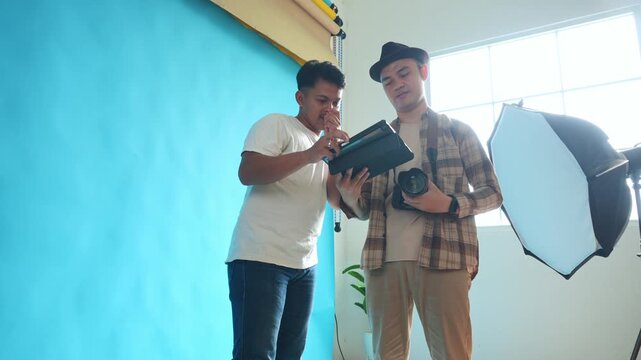 Low Angel of Photographer gives instructions to model to imitate pose on laptop