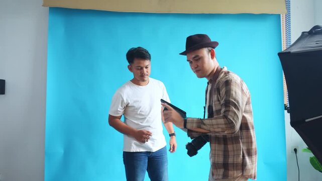 Photographer gives instructions to model to imitate pose on laptop