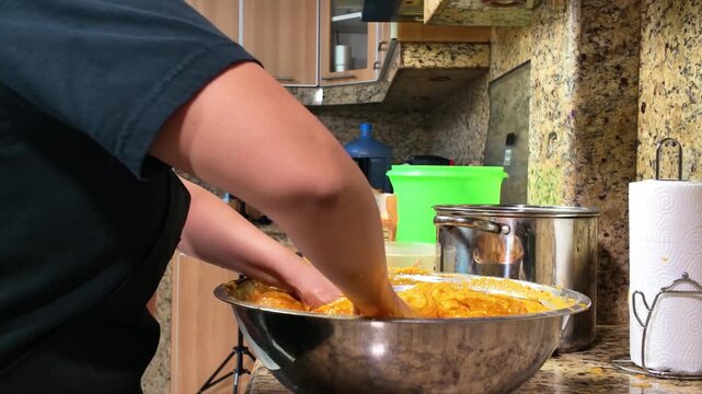 Side view of women kneading Venezuelan corn masa on a rustic kitchen, preparing traditional hallacas.