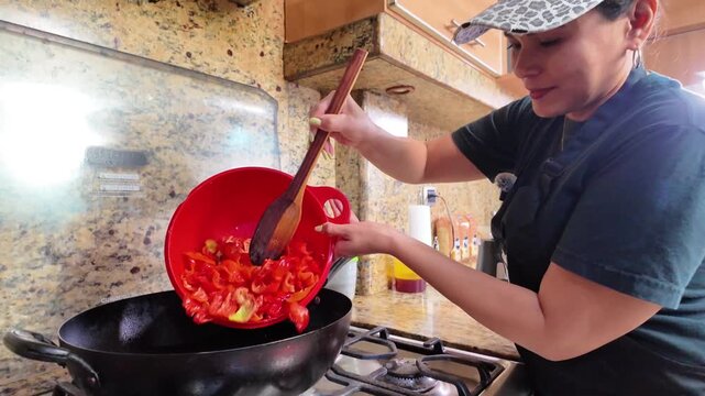Latina woman cooking aj&iacute; peppers in a home kitchen, preparing a traditional spicy sauce and showcasing authentic Latin American cuisine.
