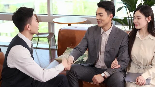 Two successful Male Business Partners In Stylish Suits Signing Contractual Document Deal. Smiling young businessman making agreement with male partner, shaking hands, establishing partnership