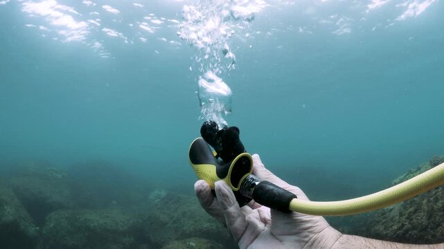 A stream of bubbles rise to the ocean surface when a scuba diving instructor releases air from his underwater breathing apparatus. Underwater view