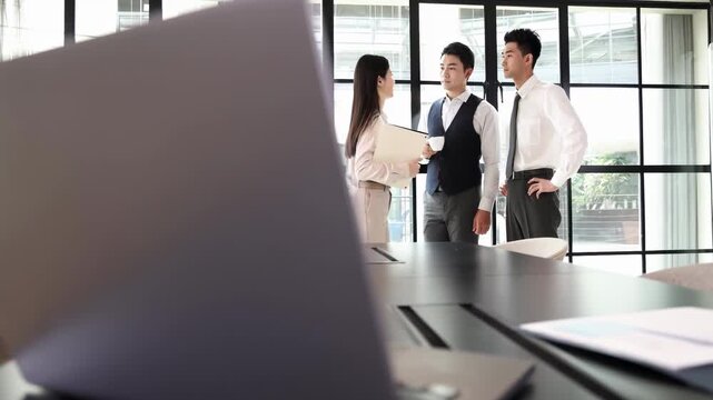 A group of business people engages in a crucial corporate colleagues actively communicating, collaborate on new project, exchanging ideas reviewing documents in modern glass office environment.