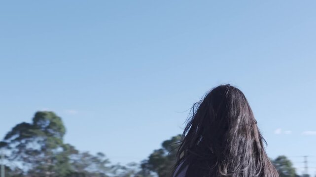 A young girl looking intently in a sunny park, framed by vibrant trees and clear blue sky, captures candid emotion. The scene conveys curiosity and intent focus.