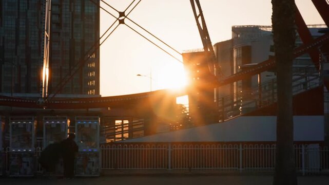 Sunset view with silhouette of person near amusement park structure in city