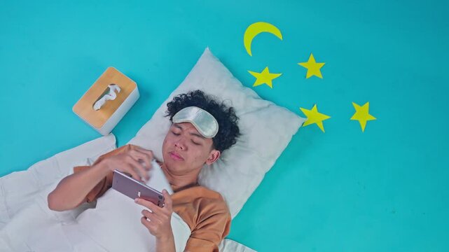 Young man lying in bed watching sad movie on smartphone and crying while using tissue