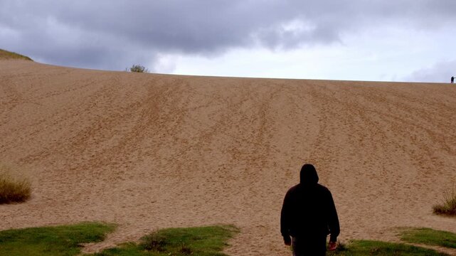 Middle aged man walking up Dune Climb at the Sleeping Bear Dunes National Lakeshore in Michigan with stable video shot.
