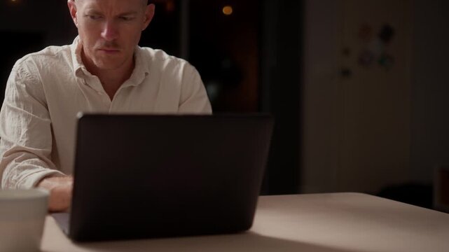 Man Working Late at Home Unaware of Suspicious Figure Outside at Night
