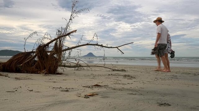 mature couple walking along the beach with some driftwood in foreground
