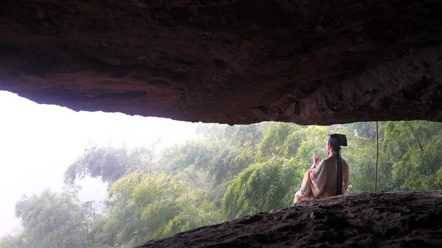 A Ming Dynasty Chinese scholar (resembling Wang Yangming) in Hanfu sits in a misty cliff cave, focused on writing with a traditional brush. A serene scene blending Chinese philosophy, cultural heritag