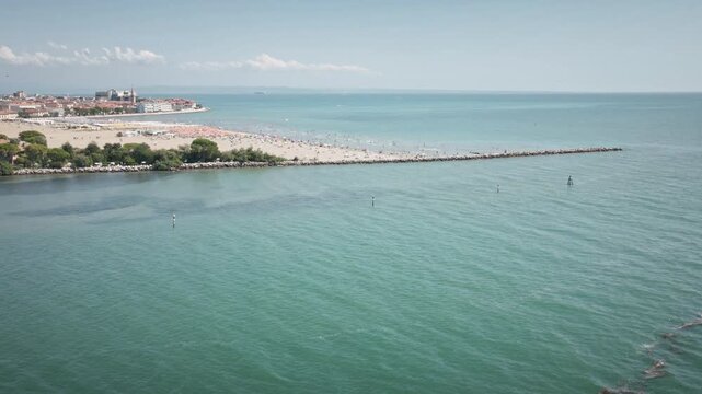 Filmed in Grado, italy, this Drone Footage captures Coastline with boats During the Day. Suitable for travel tourism in commercial projects.