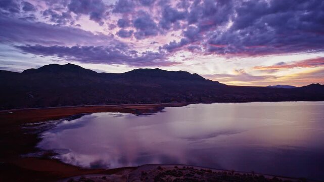 Sweeping drone shot of colorful sunrise lighting Caballo Lake State Park in New Mexico.
