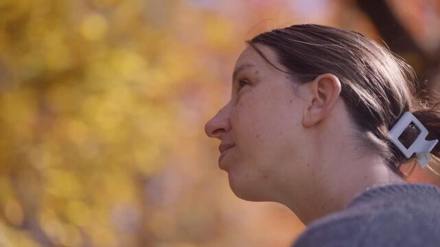 A woman admires the bright fall foliage in her backyard during autumn
