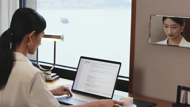 Confident businesswoman working on laptop, female office worker focused on reading documents and drinking coffee at her desk