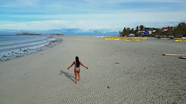 Top wide aerial composition showing island shape, palm coverage, white sand edges, and shallow water.