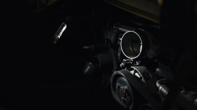 Close-up of a sports car engine being inspected with a flashlight in a dark garage. Cinematic mechanical detail showing maintenance, repair work, engineering precision, and automotive craftsmanship.