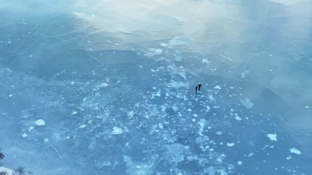 Aerial view of father holding daughter hand while skating together on frozen lake in winter