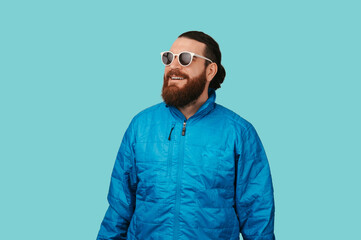 Fototapeta premium Smiling Caucasian Man Wearing Sunglasses And Blue Jacket Looking Upward With Relaxed Confident Vibe, Studio