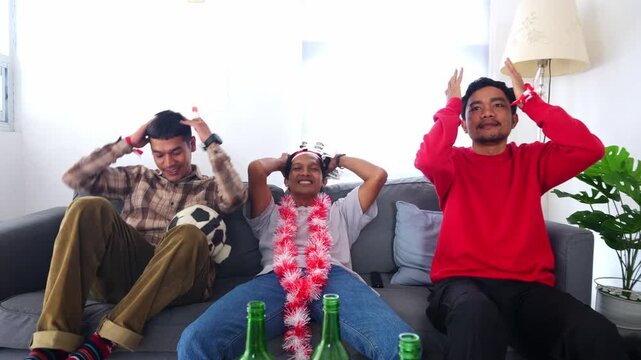 Three soccer fans react with intense shock and disappointment while watching match on TV at home