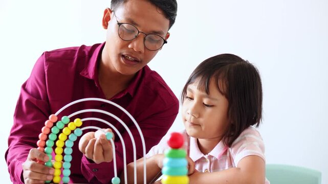 Young teacher in shirt uses colorful abacus to teach young girl math concepts