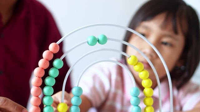 Preschool learns mathematics and counting skills with teacher using rainbow abacus educational