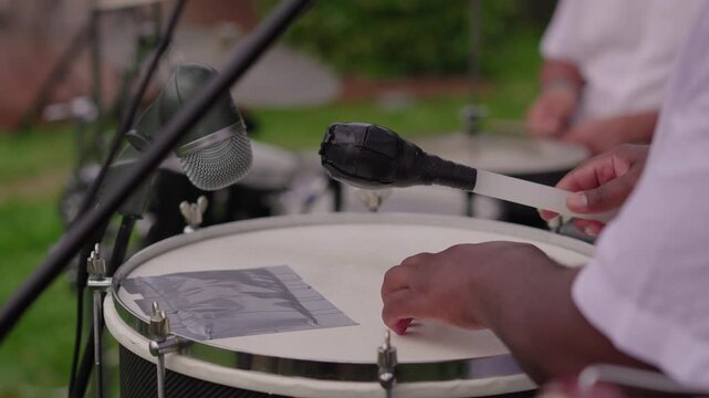 Close-up of hands striking drum with mallet during live performance
