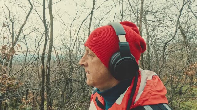 Dynamic shot of a senior runner in a red jacket navigating a snowy woodland path. Demonstrating the importance of active aging and physical health in a scenic and chilly winter environment.