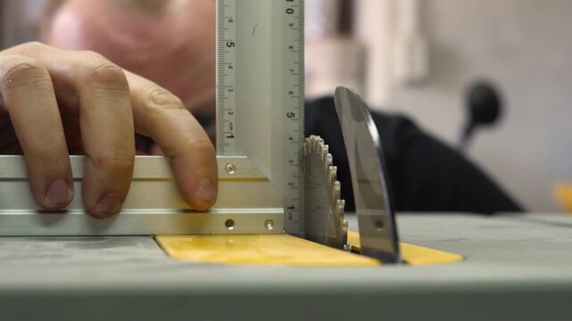 Person checks saw blade angle with a ruler in a workshop setting