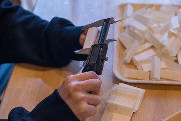 Female hands inspecting insulating material with digital caliper during manual assembly and quality...