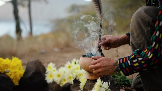 Feather stirs incense smoke over altar during Mayan ceremony