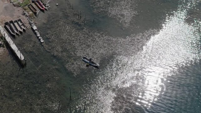 Single wooden canoe glides over shallow waters of Lake Atitlan in Santiago Atitlan Guatemala