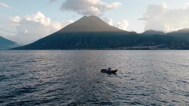 Single canoe floats on Lake Atitlan with volcanic mountains in Guatemala