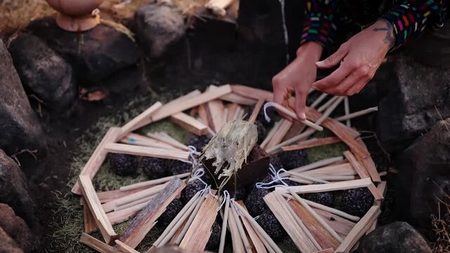 Hands arrange ocote wood for Mayan fire ceremony at Lake Atitlan in Guatemala