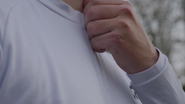 Hand pulling zipper on light jacket while preparing for outdoor exercise