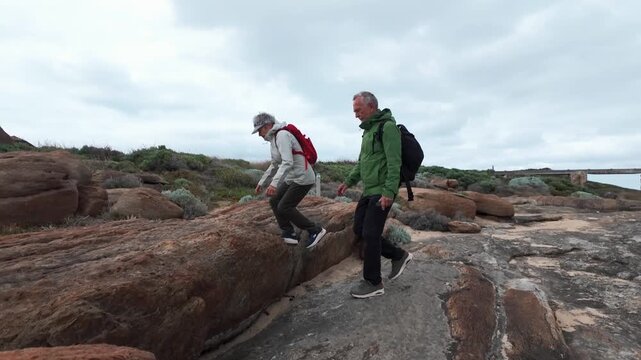 mature couple in trekking outfits walking along the rocky sea coast in the vicinity of Cape Leeuwin