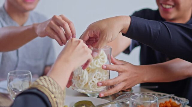 Happy Family sharing traditional kerupuk crackers while dining together during Eid celebrations
