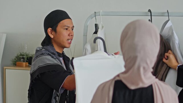 Muslim salesman offering white robes to buyers at Muslim fashion store