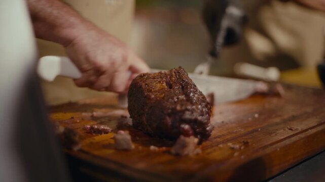 Hand slices tender, dark meat on rustic wooden board. Cook's focus shows care in preparing dish. Warm, inviting scene hints at home-cooked meal. Great for food, cooking, or restaurant marketing