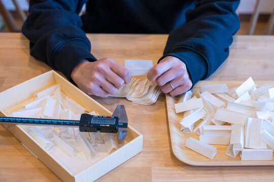 Female hands folding insulating material pieces in manual assembly and piecework production process