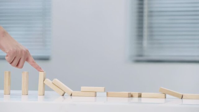 Problem solving closeup of business hand stopping the fall of wooden block like domino effect for stopping business planning and strategy risk protection to make business growth