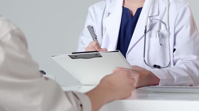 Concentrated doctor physician or cardiologist filling out medical report form, giving consultation to patient in clinic about wellness, nutrition, health care, answering questions, giving advices and